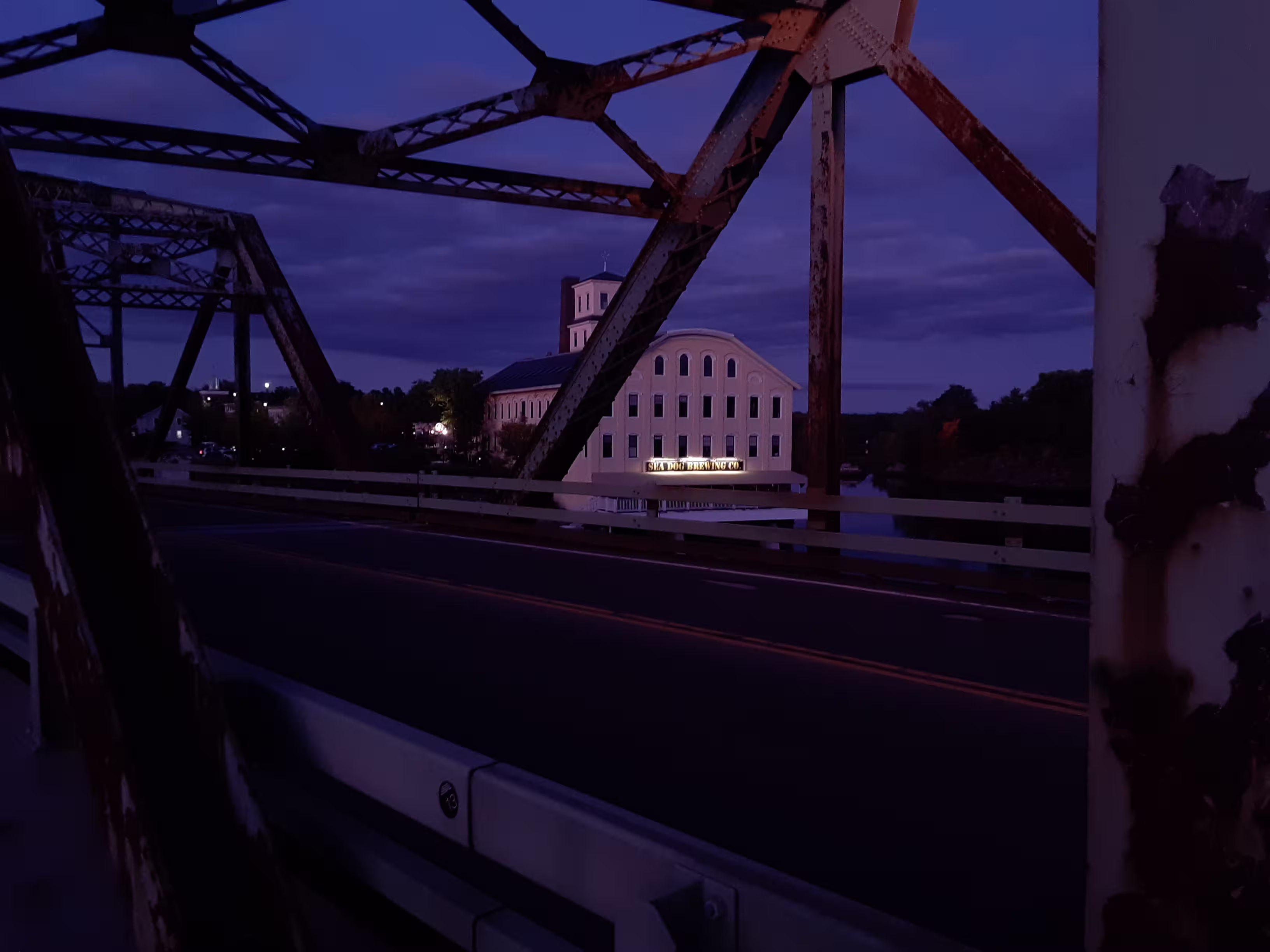 Image of the Sea Dog Brewing Co as seen from a rusty bridge.