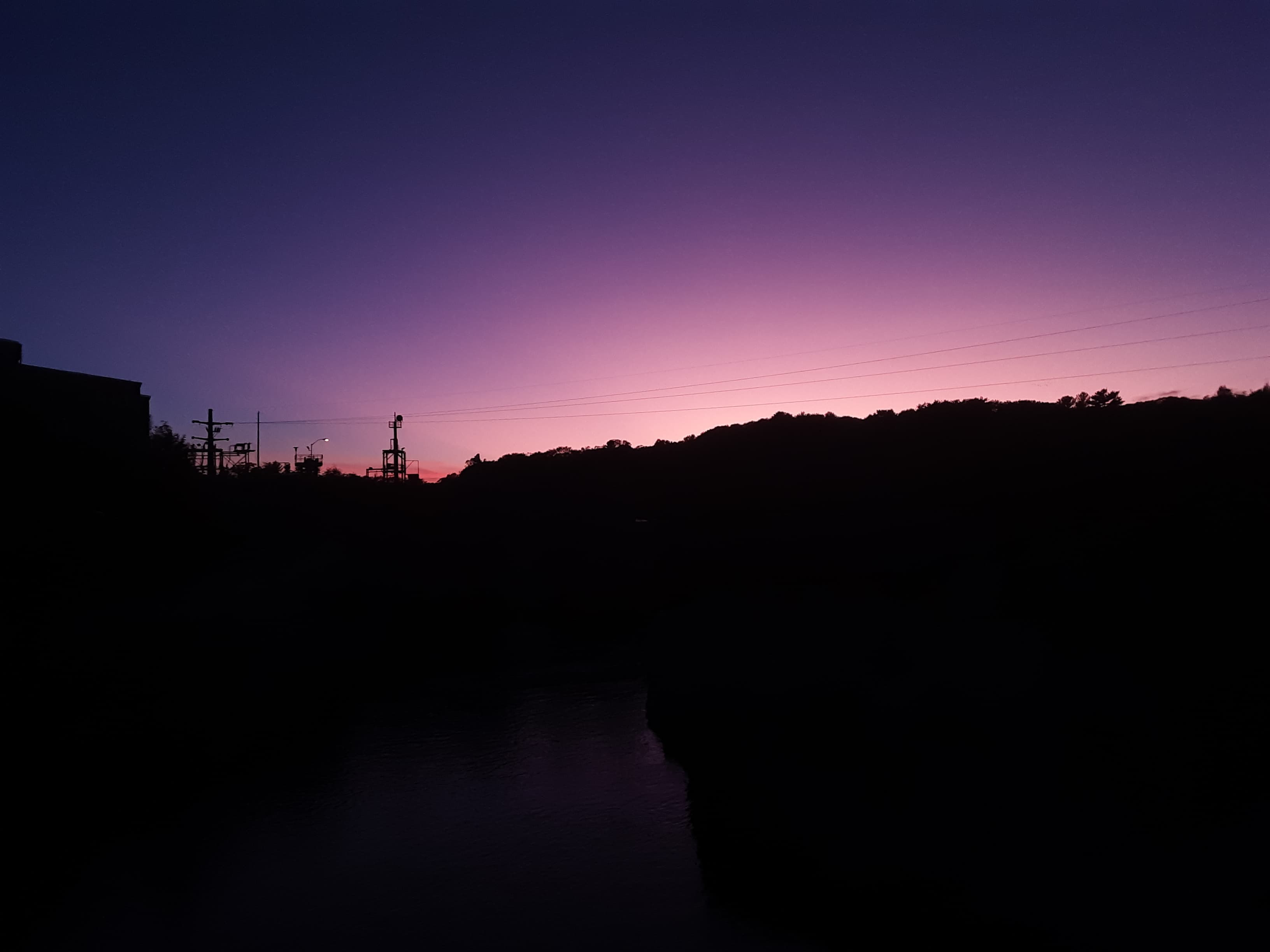 Image of a sunset with the silhouette of power lines.